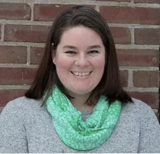 woman with brown hair and green scarf smiling