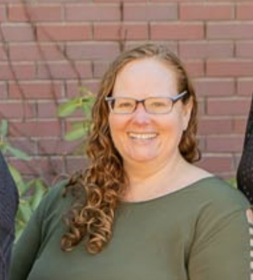 Women with light brown hair and glasses, smiling