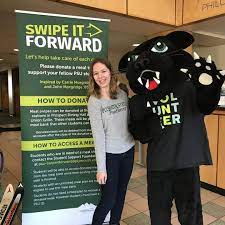 photo of woman smiling next to person in panther suit and "Swipe it Forward" sign