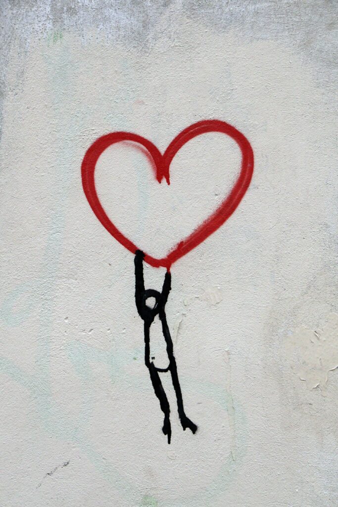 Stick figure man holding up heart