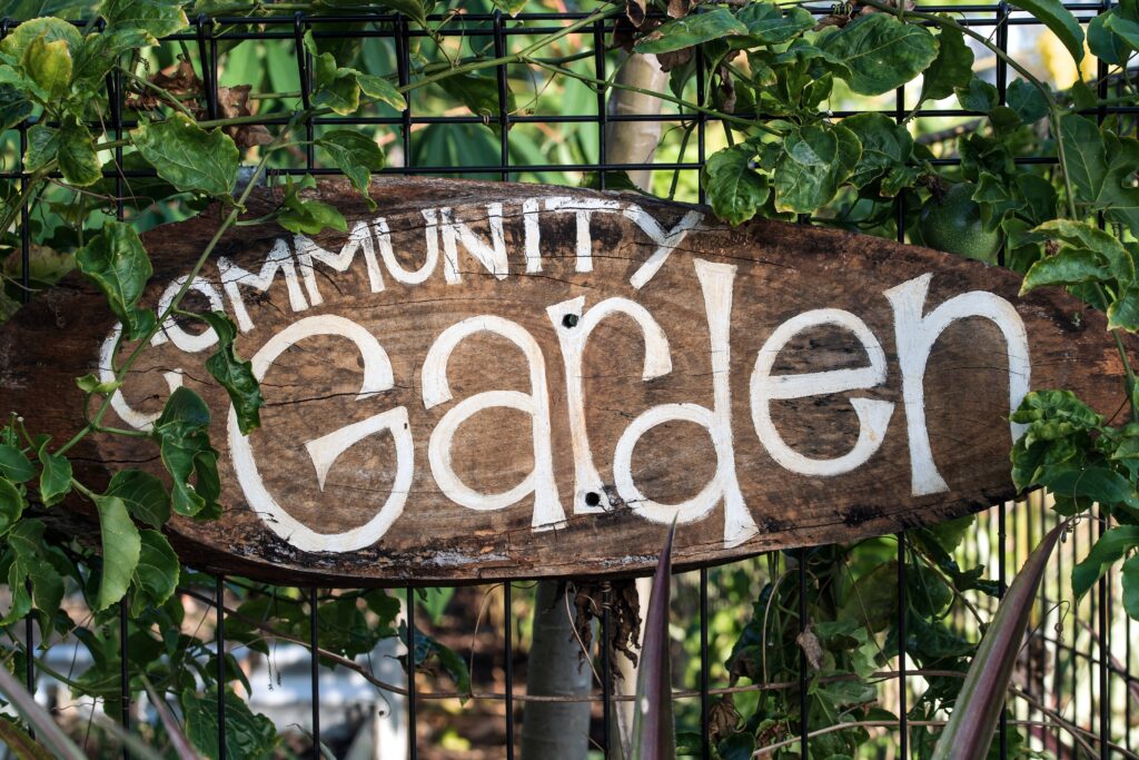 sign that says community garden covered in foliage