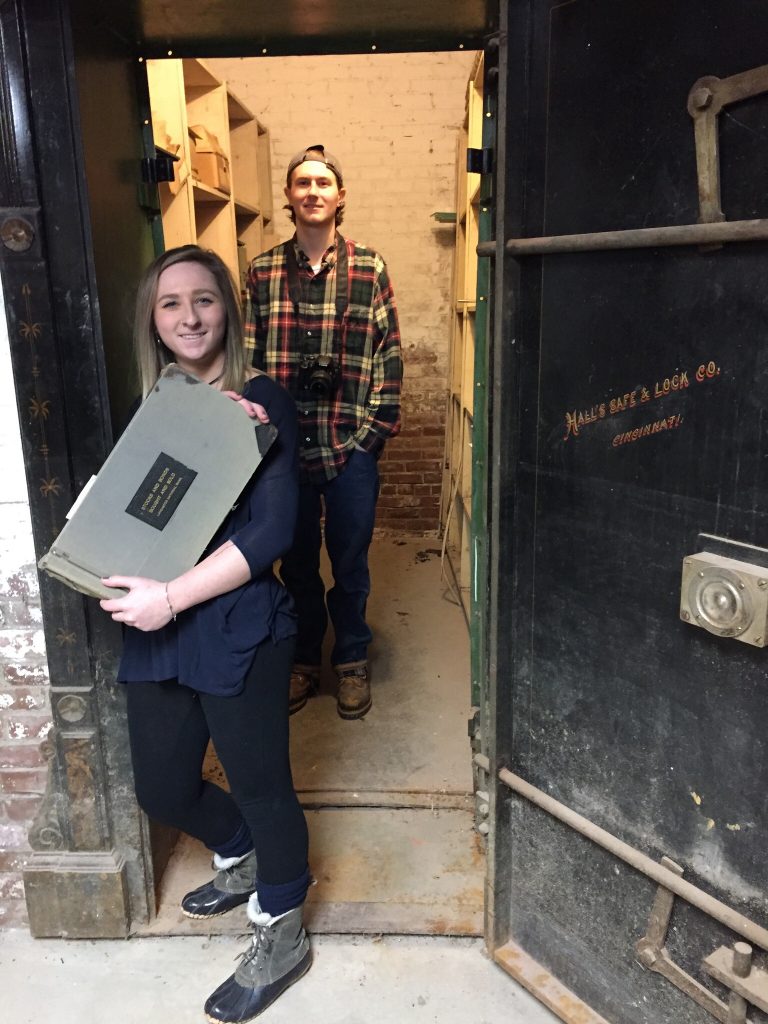 Two students in a closet holding an old book they found