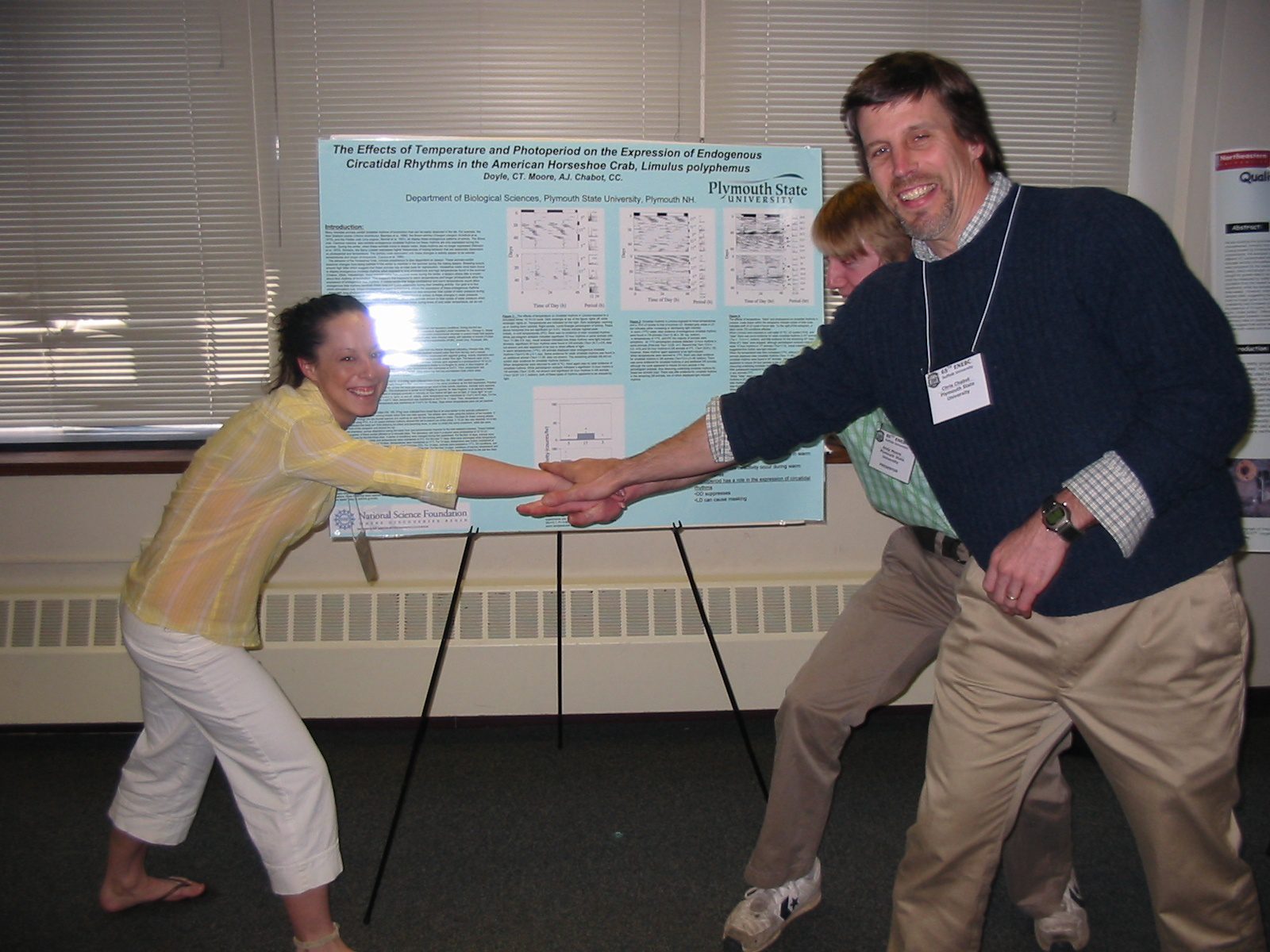 Professor Chabot high-fiving student in front of poster