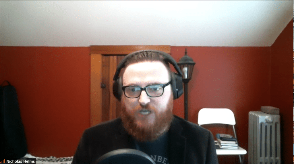 Man speaking into microphone with headphones on from home