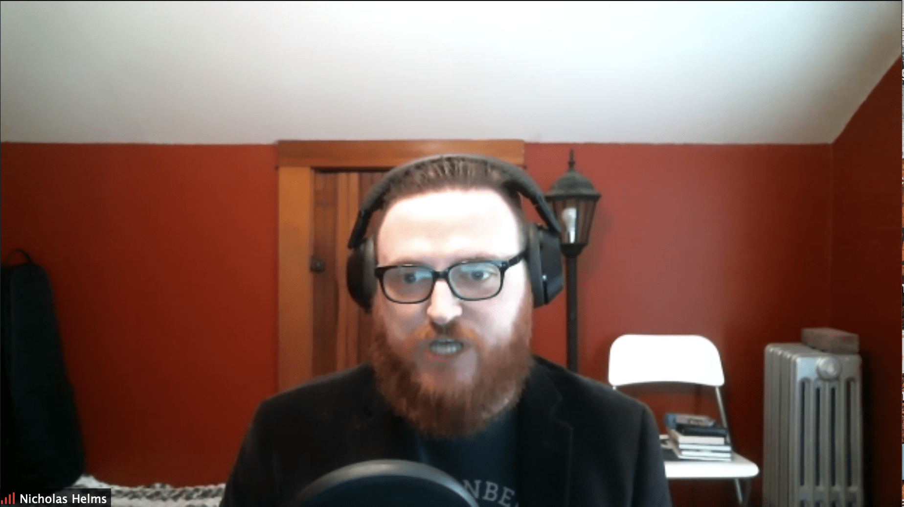 Man speaking into microphone with headphones on from home