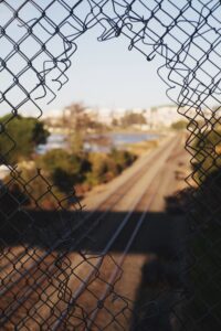 image of a broken fence with a scene beyond of a train track