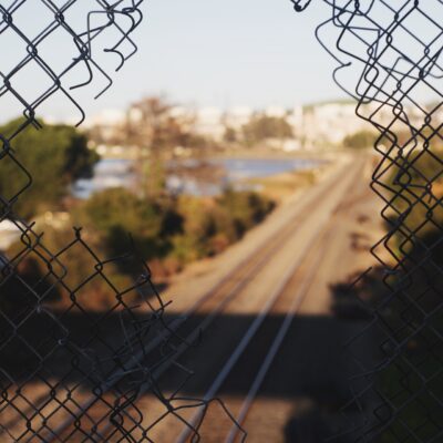 image of a broken fence with a scene beyond of a train track