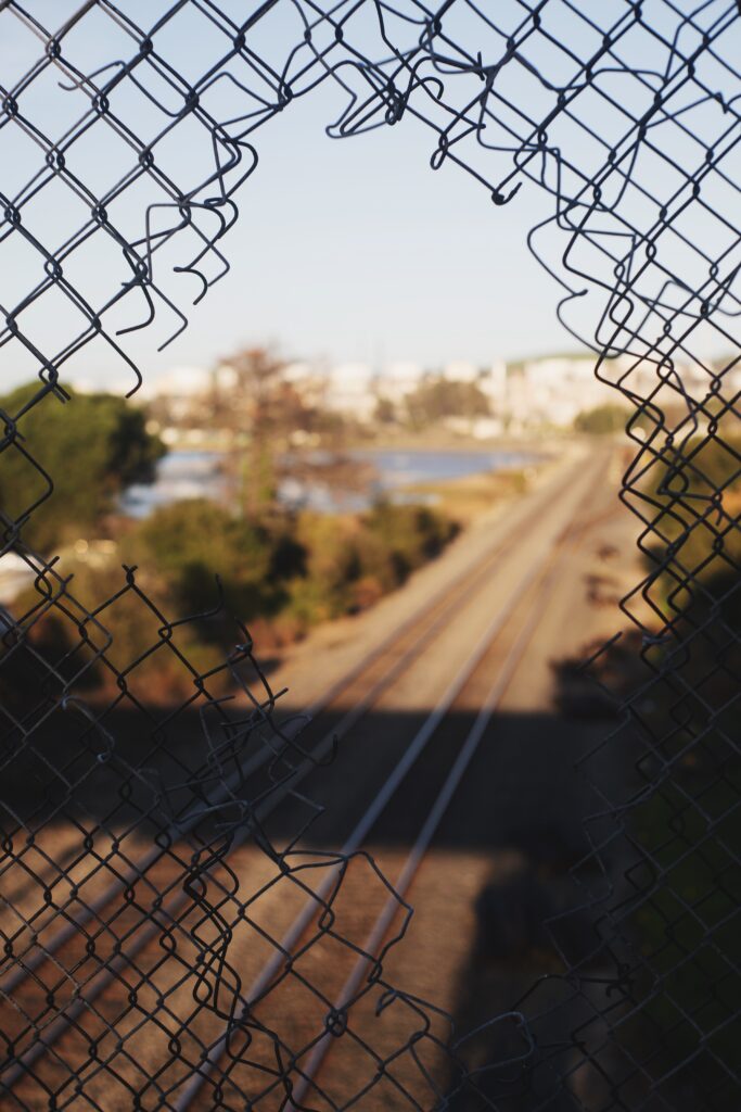 image of a broken fence with a scene beyond of a train track