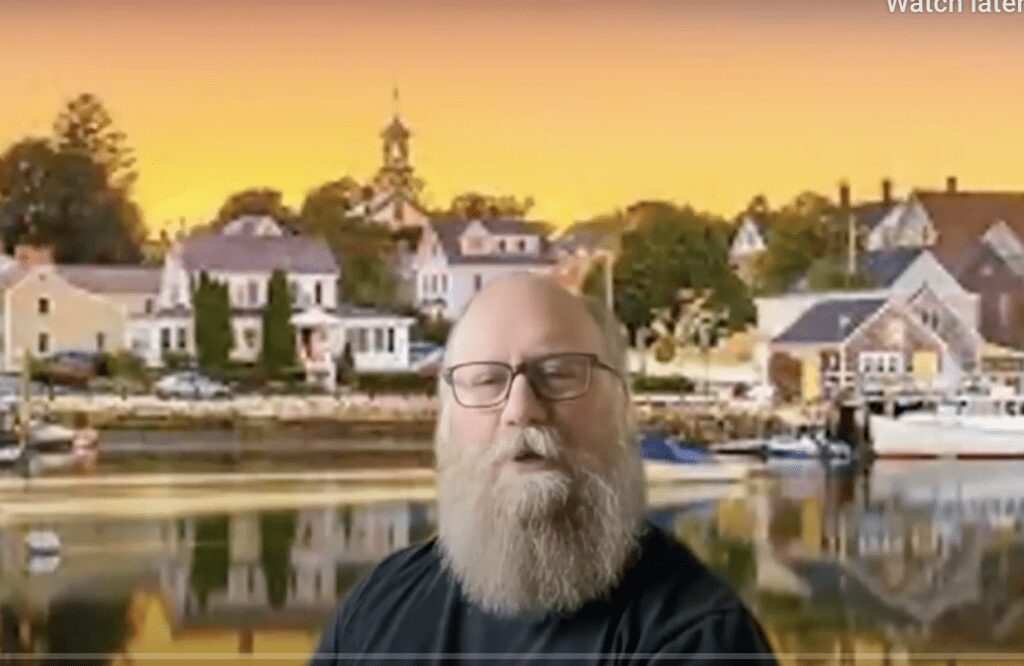 Screenshot of bearded man in front of a water scene