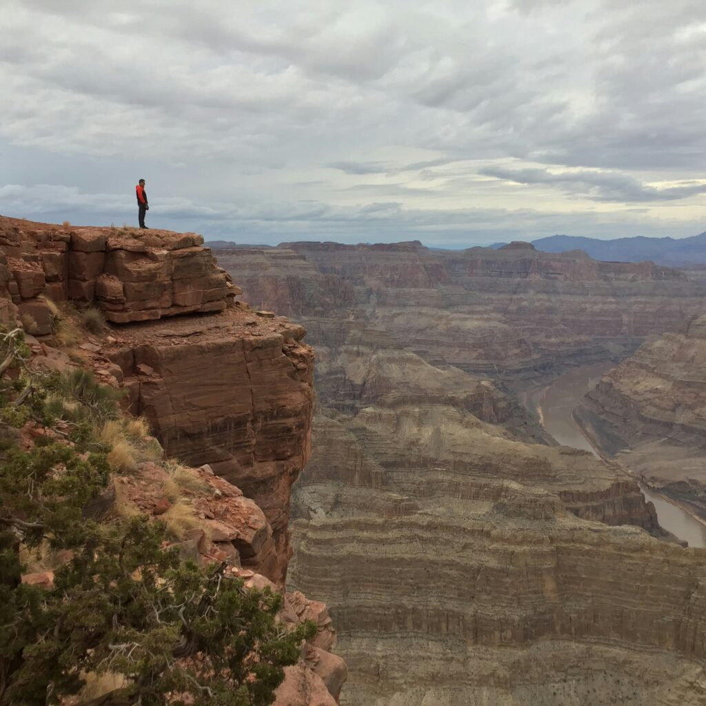 Man standing at the top of a canyon looking out to the chasm